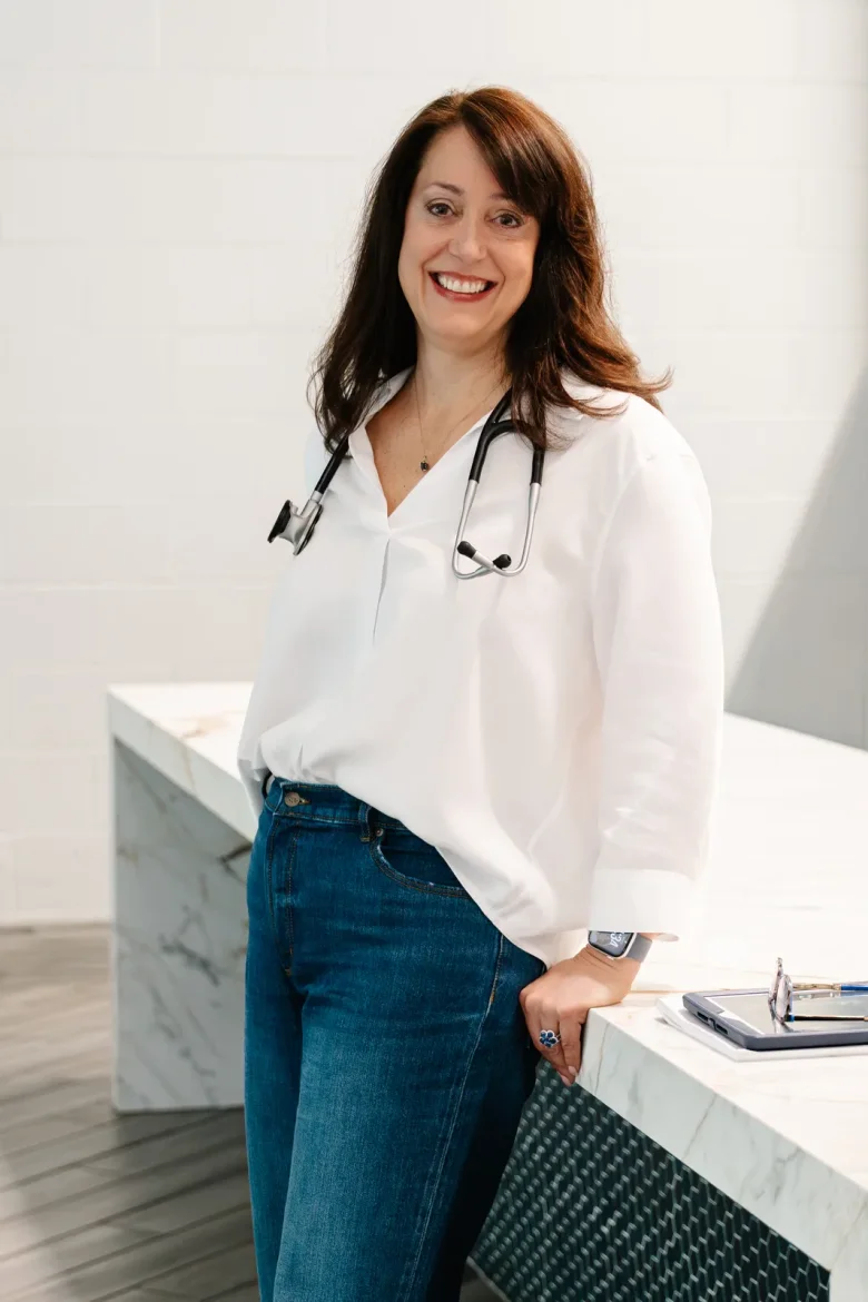 Christine DiNoia, BSN, RN seated at her desk with a stethoscope