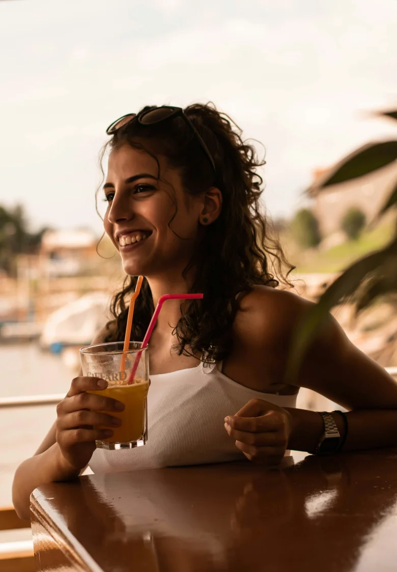 Woman in a white tank top holding a glass of water