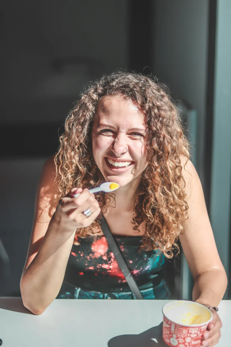 Woman smiling with a spoon and cup at a table