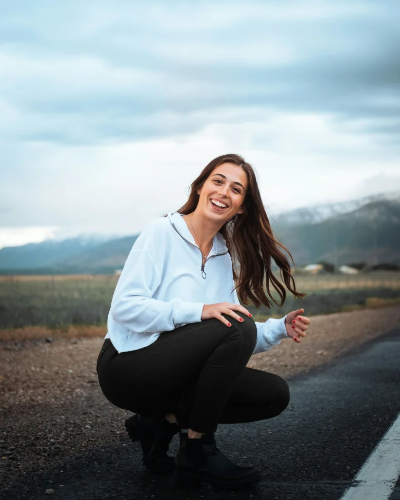 Woman in a white shirt sitting outdoors on pavement